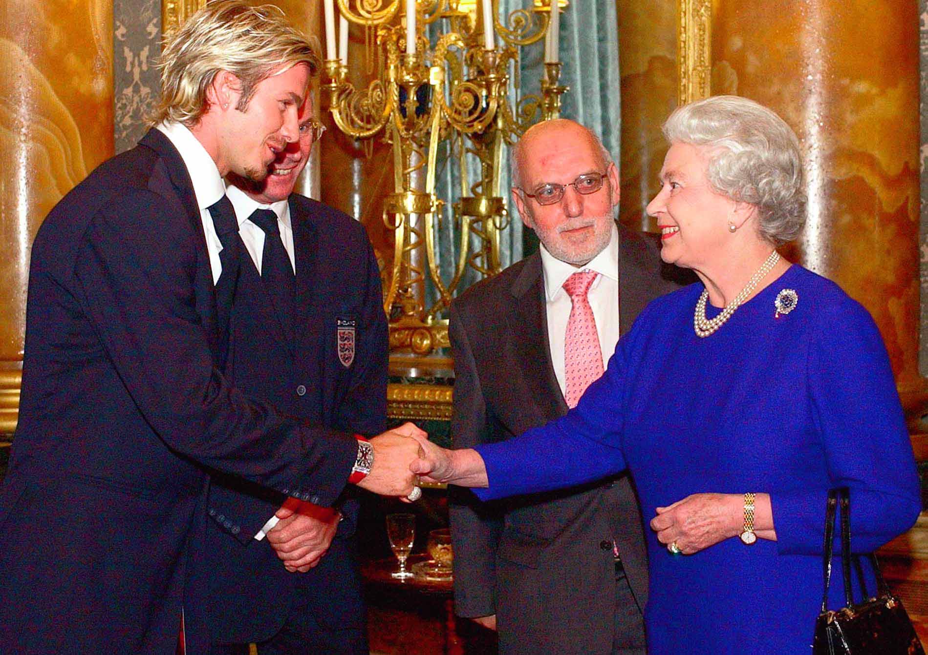 Britain’s Queen Elizabeth II meets England soccer captain David Beckham, watched by English Football Association Chairman Geoffrey Thompson, and England coach Sven Goran-Ericsson, partly hidden, during a reception for the Football Association held at Buckingham Palace in London, Tuesday Nov. 19, 2002. The 75-strong England party included backroom staff as well as high profile players and management.(AP Photo/Kirsty Wigglesworth/pool)