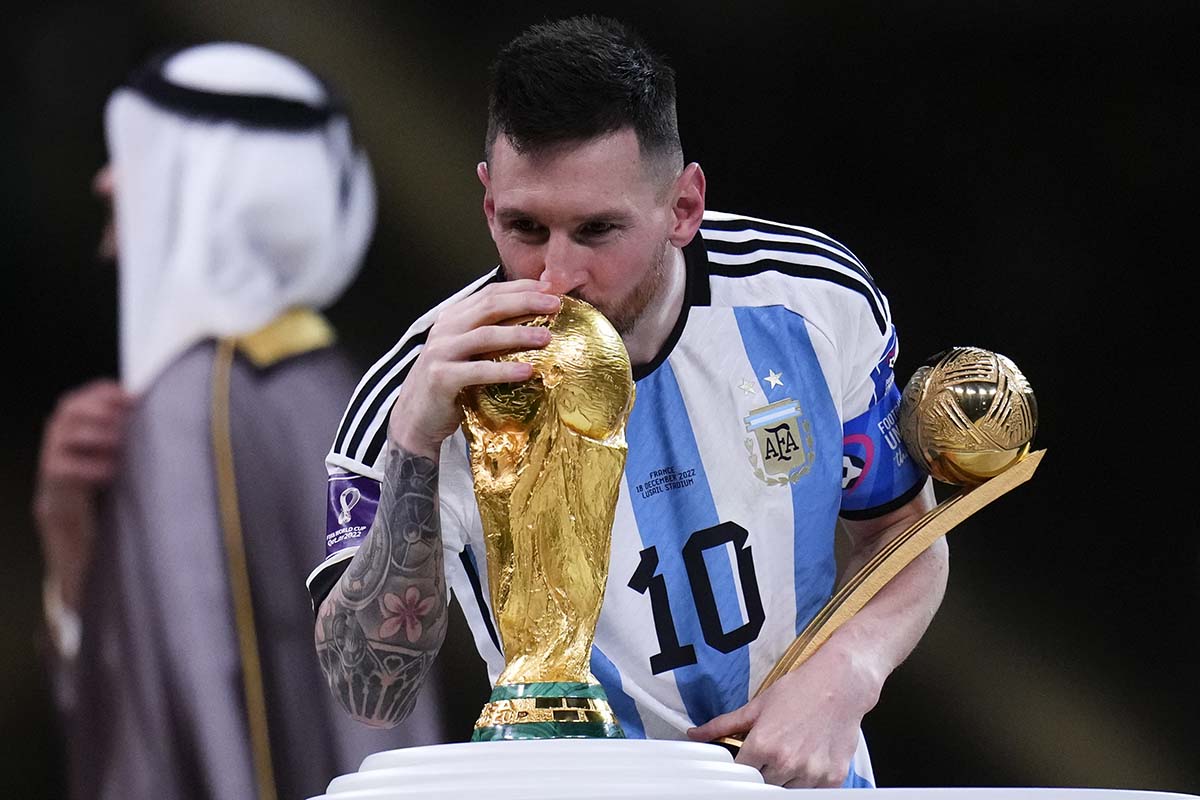 Argentina's Lionel Messi kisses the World Cup trophy as he holds the the Golden Ball award for best player of the tournament, after the World Cup final soccer match between Argentina and France at the Lusail Stadium in Lusail, Qatar, Sunday, Dec.18, 2022. (AP Photo/Manu Fernandez)